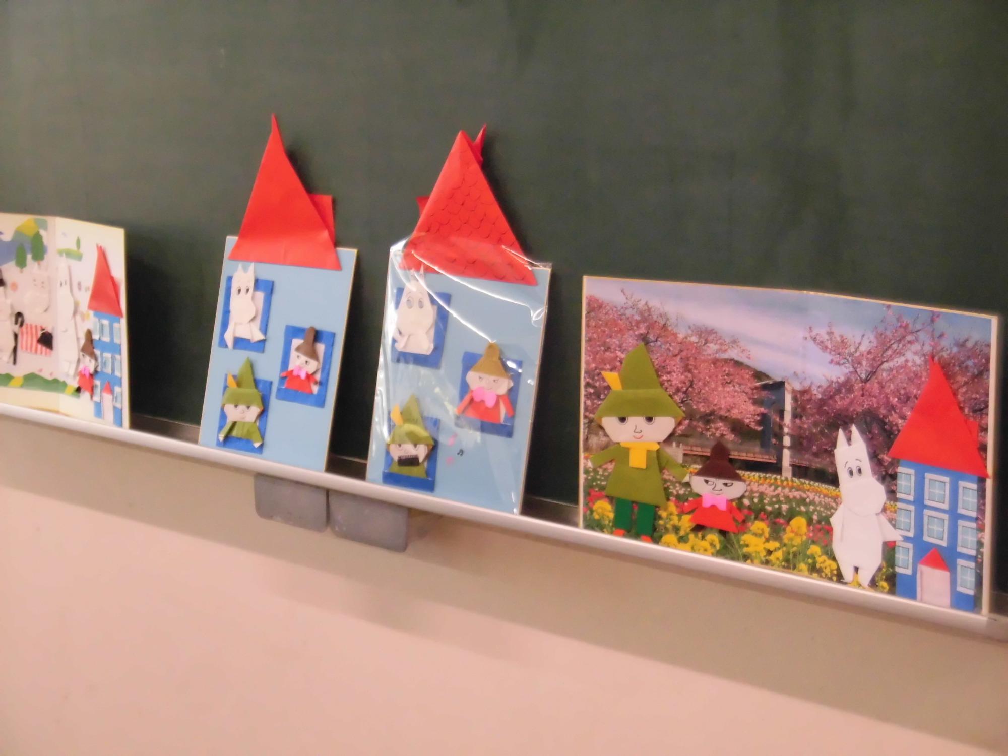 黒板の下の棚に並べられた、ムーミンのキャラクターたちをモチーフにしたカラフルな手作りの工作作品を写した写真