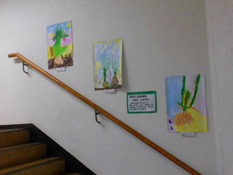 階段の壁に、植物をテーマにした子供たちの絵が展示されている様子を写した、子どもの作品展示の写真
