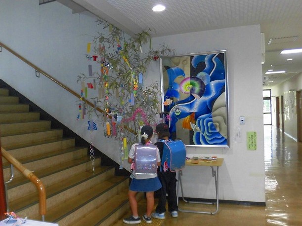 二人の子供が笹に飾りをつけている後ろ姿を写した、七夕飾りの写真