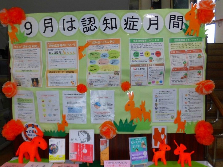 緑色の掲示板に「9月は認知症月間」と書かれ、認知症に関する様々な情報やパンフレットが掲示されており、オレンジ色のウサギの飾り付けが施されている展示写真