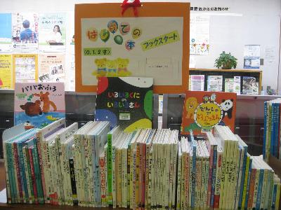 木製のカウンターの上に沢山の本が並んでおり、中央に「いろいろくにのいろいろさん」の表紙が見える絵本が置かれた図書室の乳幼児向け絵本コーナーの様子の写真