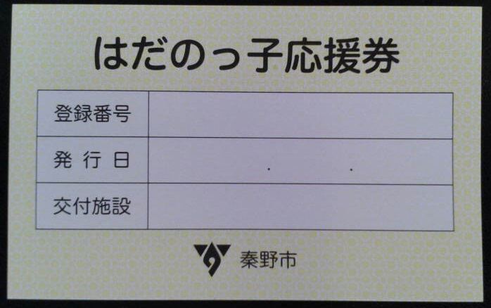 黄色い用紙に印刷された「はだのっ子応援券」という見出しと、登録番号・発行日・交付施設の記入欄がある表、そして下部に秦野市のロゴマークが配置されたはだのっ子応援券の写真