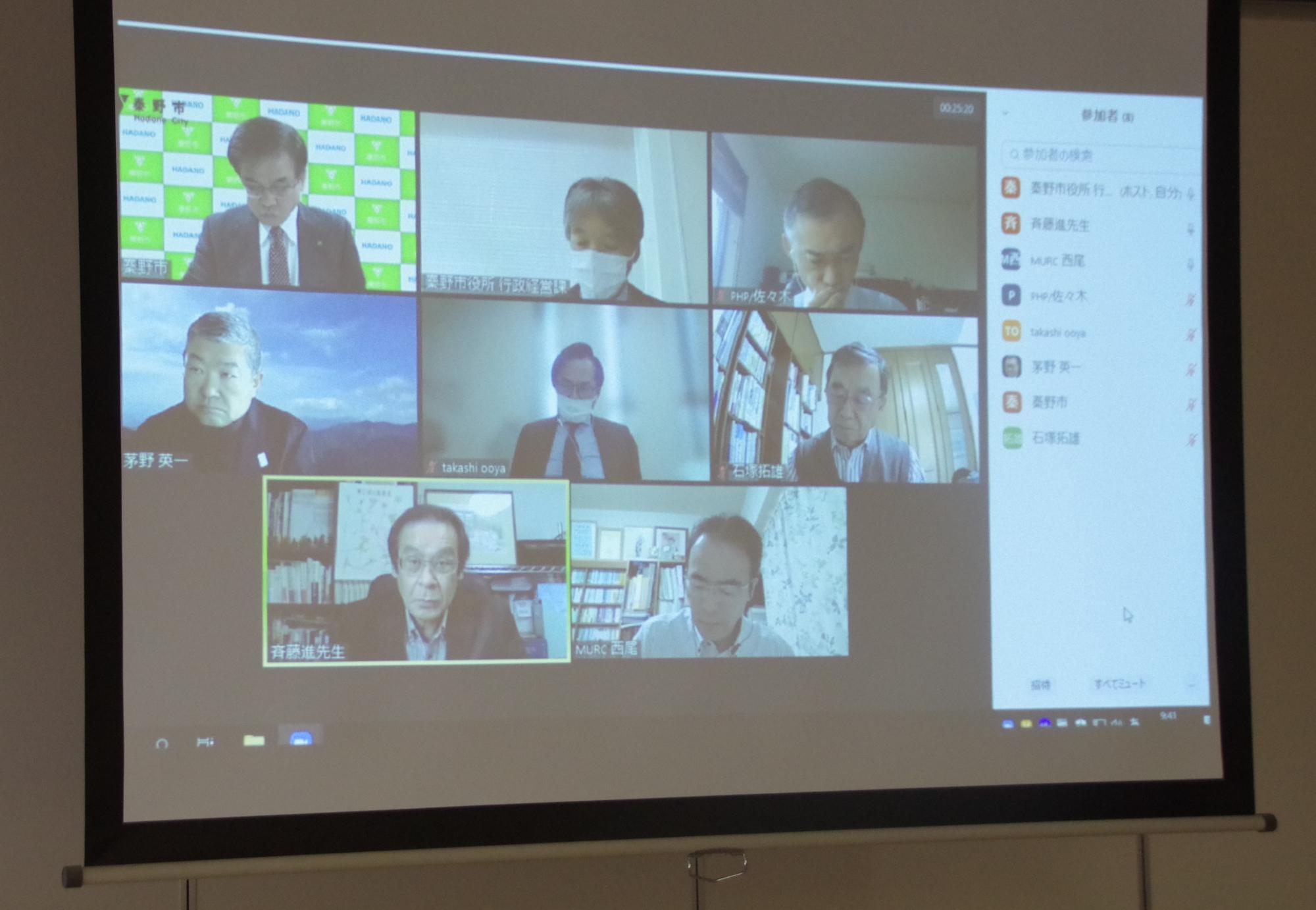 8名の参加者が3行2列のグリッド表示でオンライン会議に出席し、左下の参加者が発言中であることを示す緑色の枠で囲まれているビデオ会議の画面写真