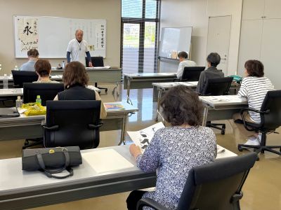 机を並べたところに10人ほどの人が座り講習を受けている