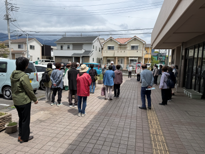 多数の人が公民館の駐車場で集まり避難訓練をしている