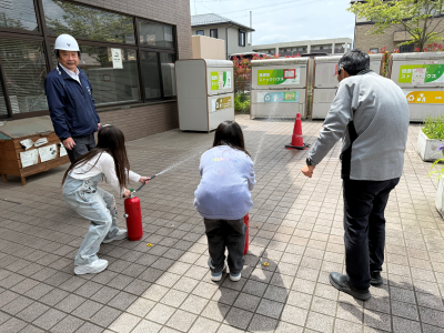 子ども2人が水消火器の練習をしているのを大人が2人指導している