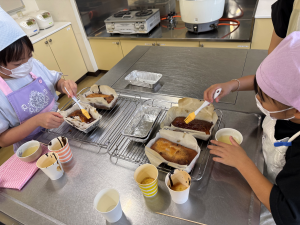 焼けたパウンドケーキに子どもたちがシロップを塗っていいる