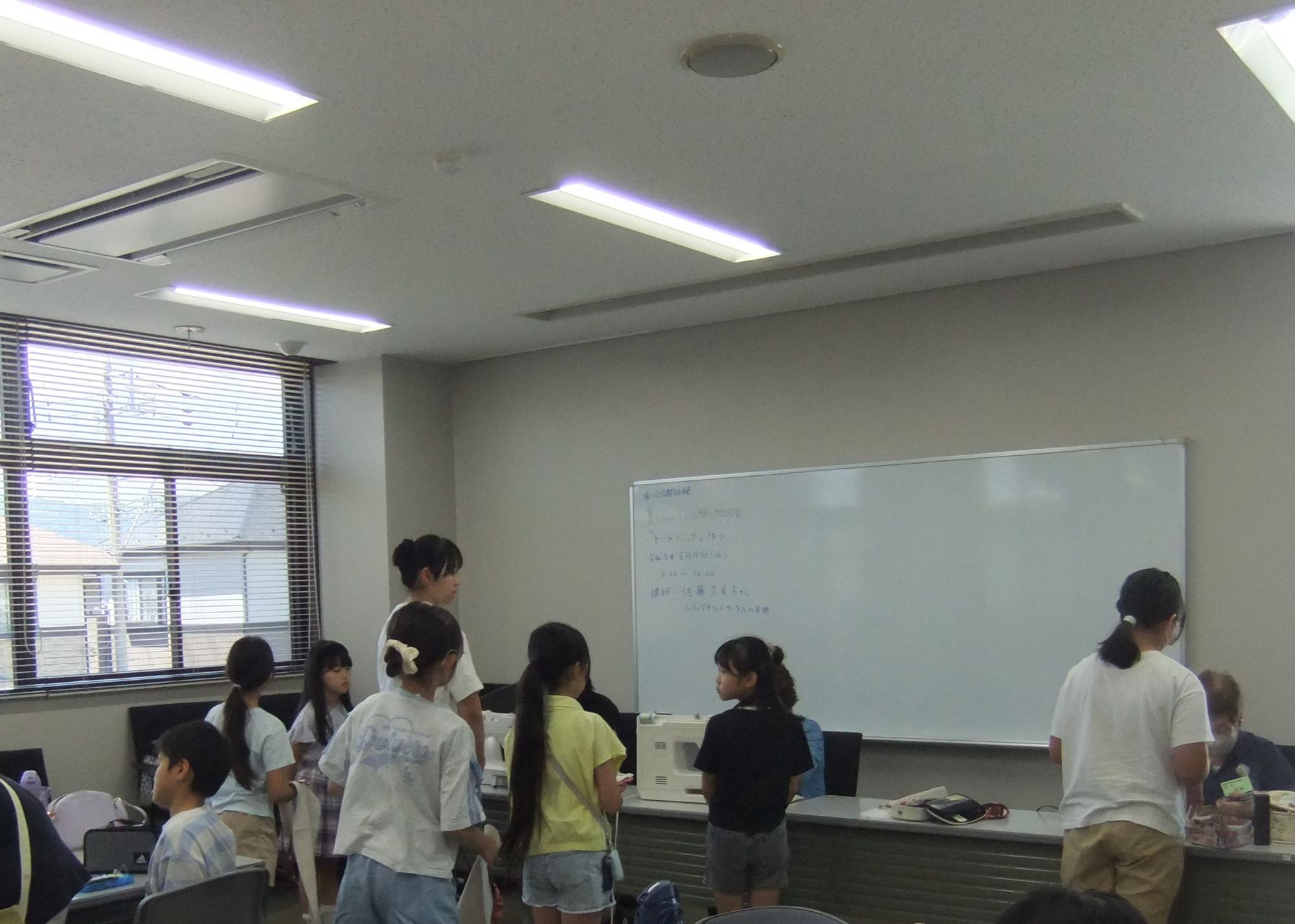 子どもたちがミシンの前に並んでいる