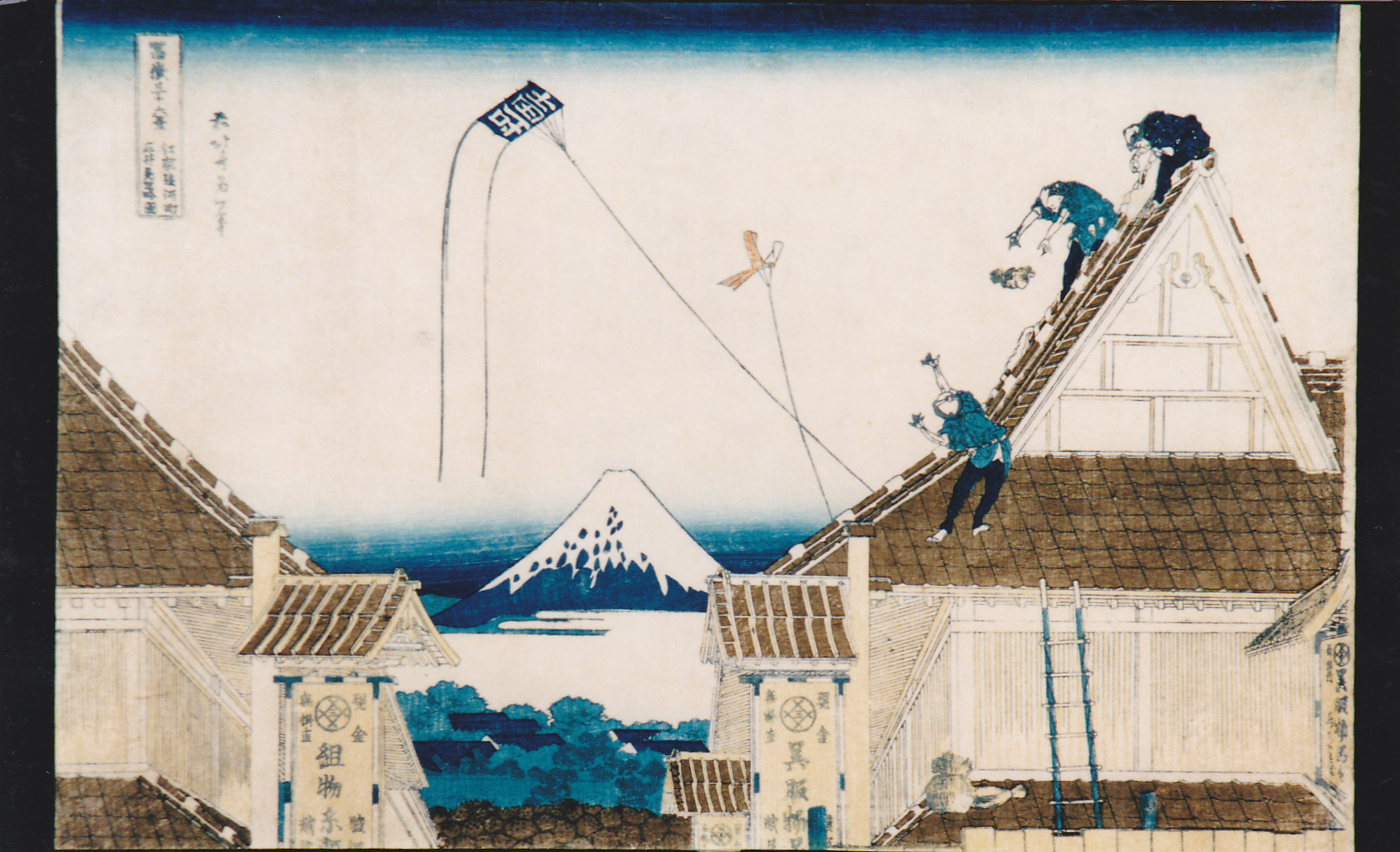 遠景には大きな屋根の間に富士山が見える家の屋根の上で3人の男性が凧揚げをしており、そのうちの一人がバランスを崩して落ちそうになっている様子を描写している賑やかな浮世絵