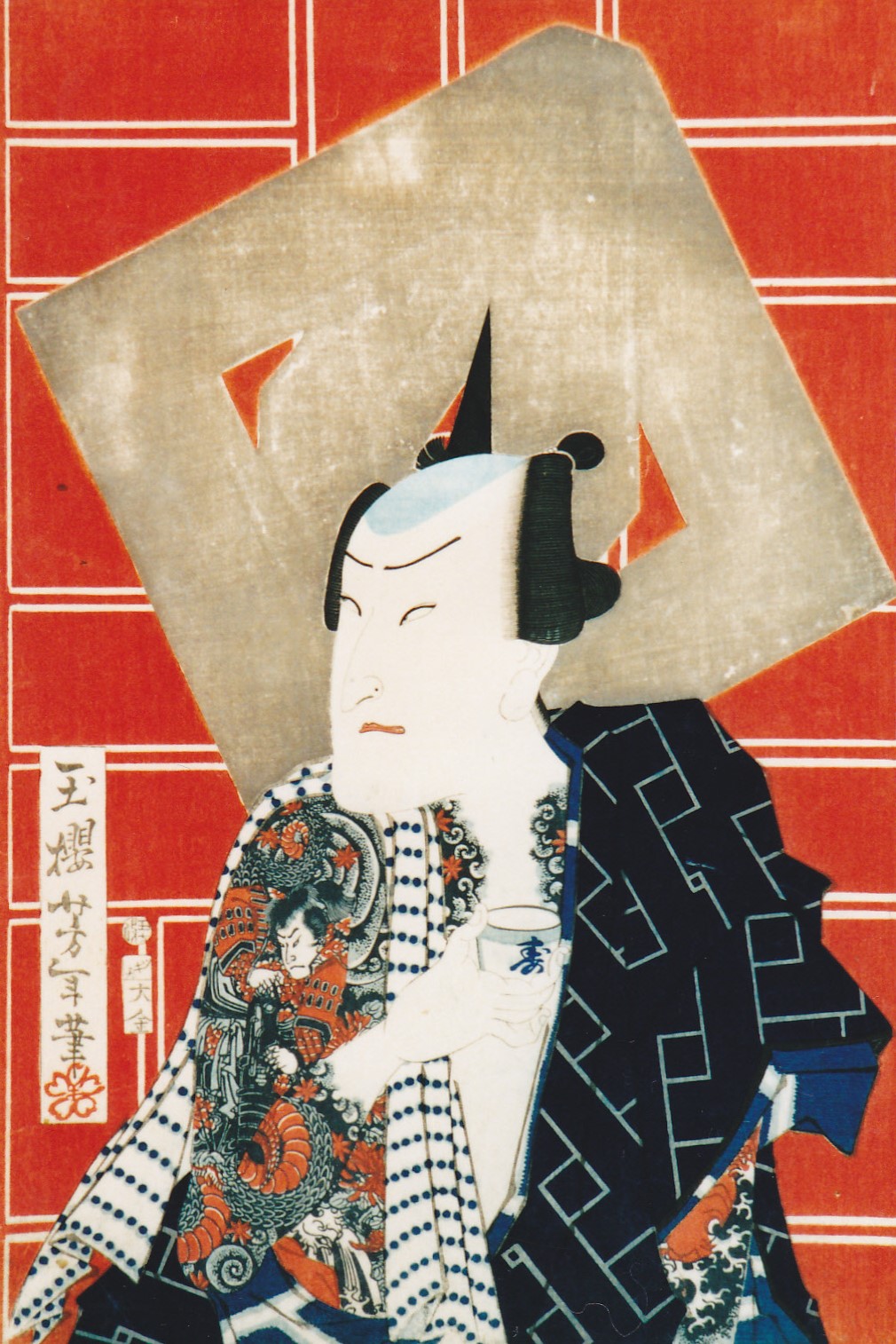 真っ赤な背景と大きな纏の背景に、黒い着物と刺青を施した男性が、髪を整え、盃を持っている様子が描かれた浮世絵