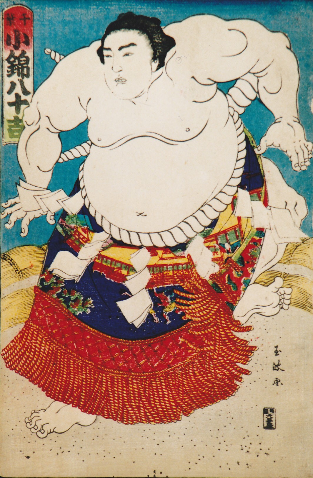 上半身裸の力士が、白いまわしと赤や青色が入った化粧まわしを身につけて、両手と両足を大きく広げて土俵上に立つ初代小錦八十吉の姿を描いた、歌川国芳による迫力ある相撲絵の浮世絵