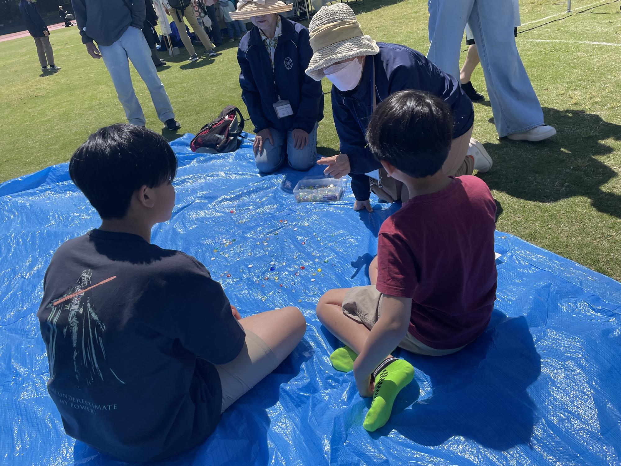 おはじきを教える民生委員とこども