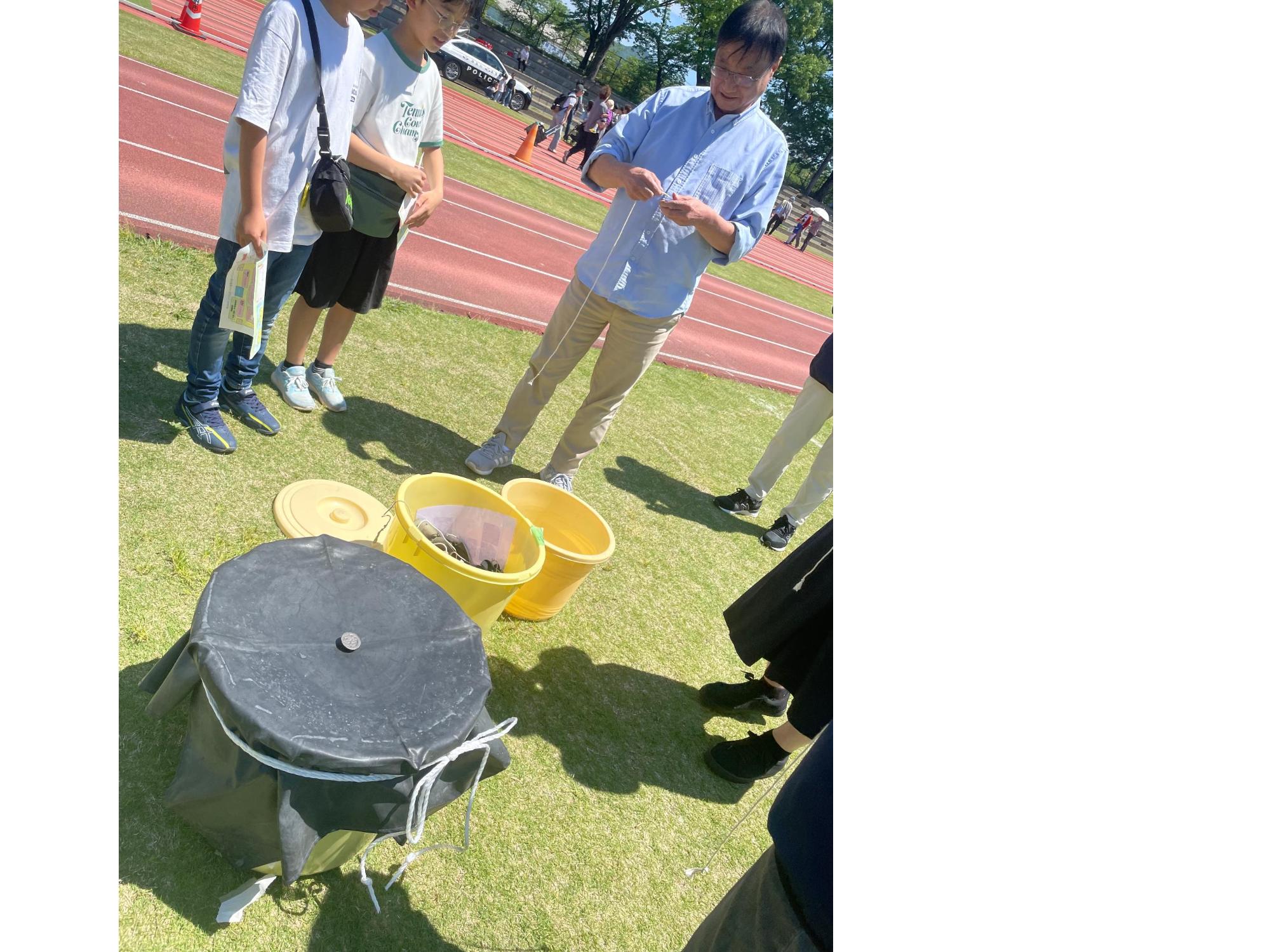 ベイゴマのやり方を教える民生委員とこども