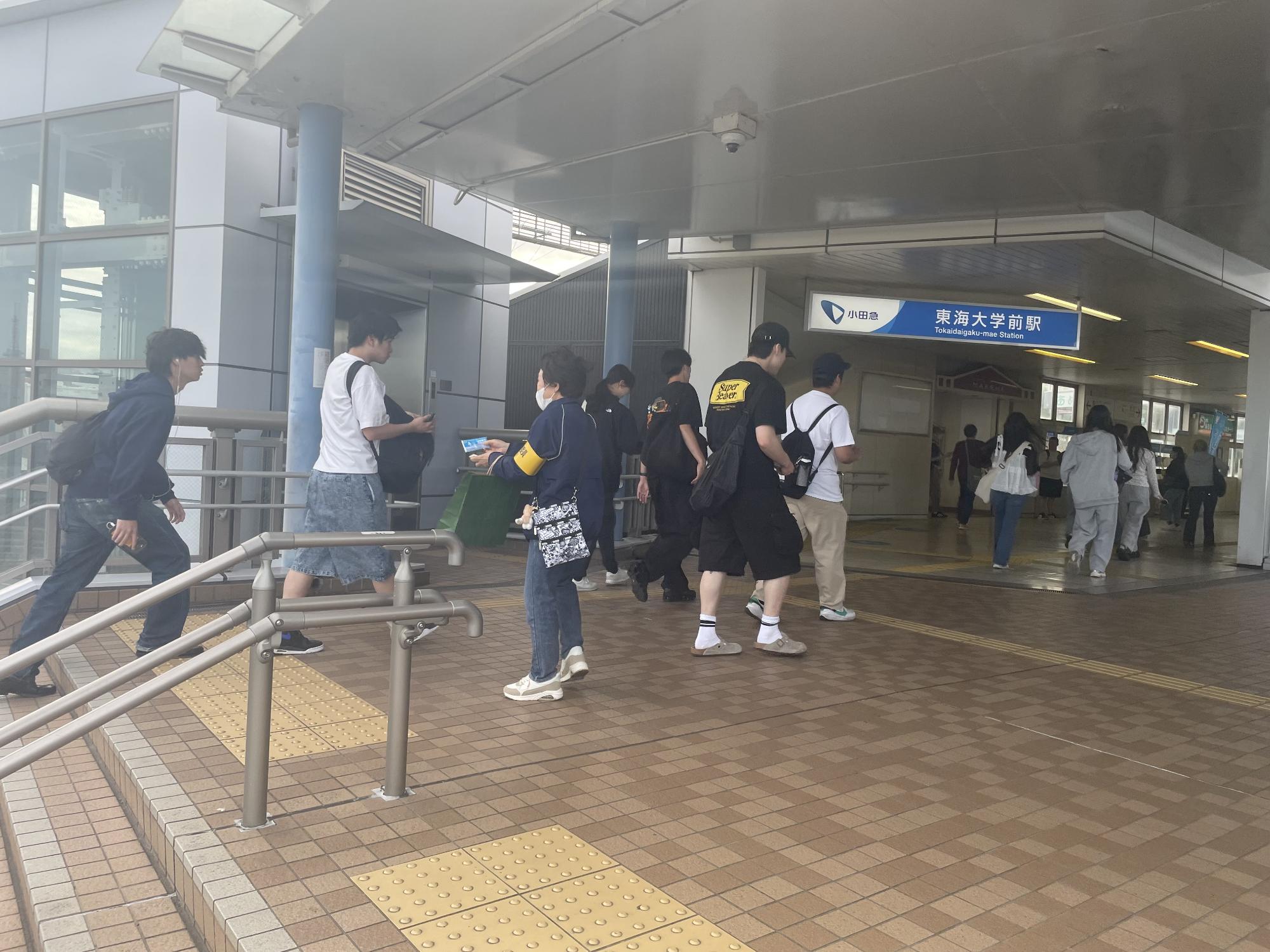 東海大学前駅で民生委員がポケットティッシュを手渡す様子