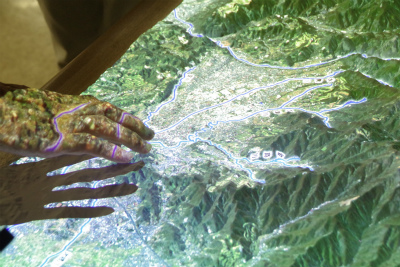 映像が投影された立体模型に2人が手を触れている写真