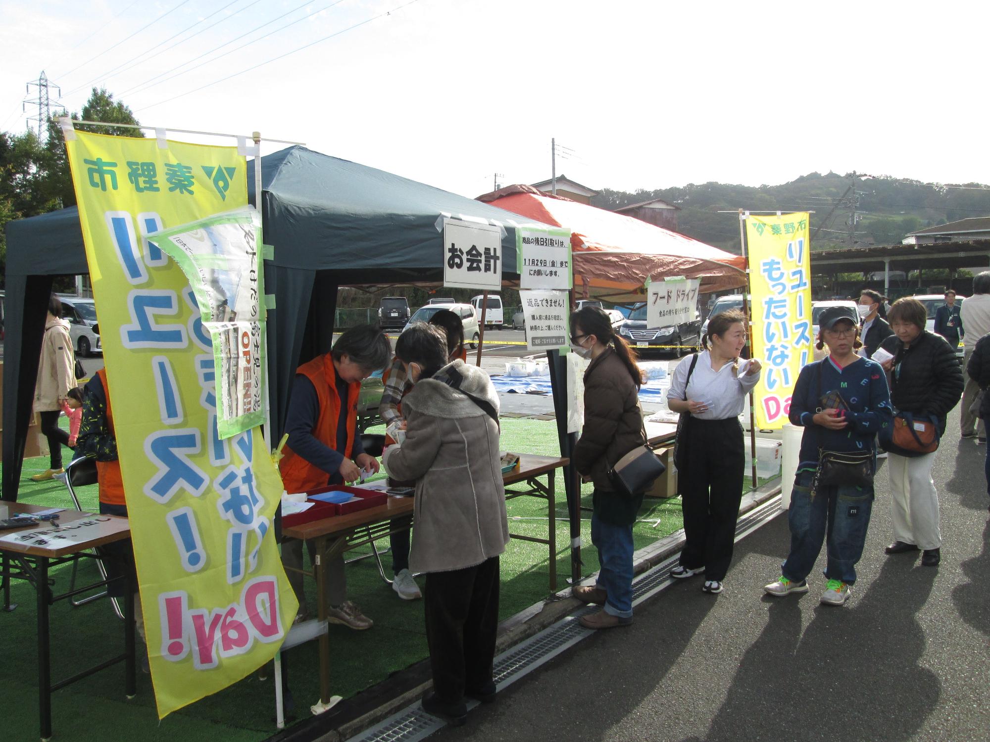 黄色の幟が立てられたブースで、たくさんの人々が、リユース品を購入している様子を写した写真