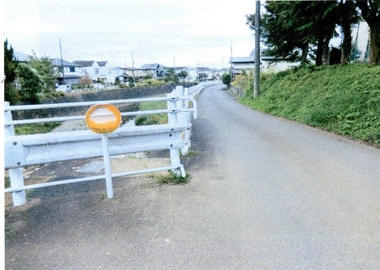 ガードレールの支柱に丸いオレンジ色の反射板の破損を示す写真