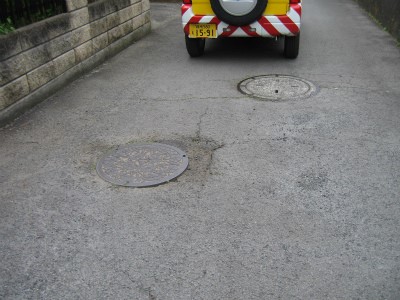 マンホール周辺の舗装がひび割れて穴及び段差を示す写真