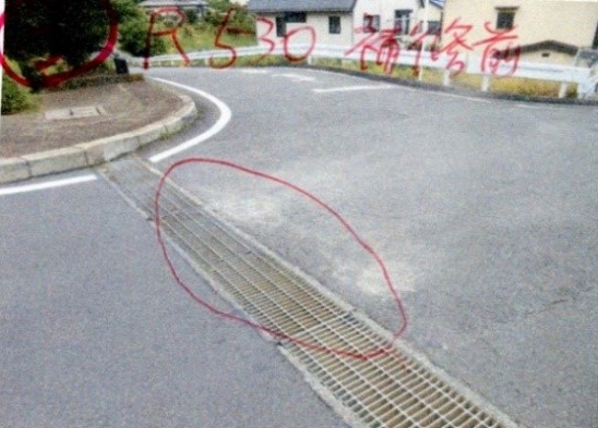 長い金属製の排水溝の蓋が、路面より沈下して段差が生じた段差を示す写真