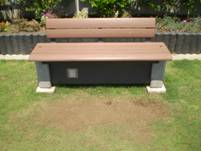 屋外の芝生に設置された木目調のベンチで、背もたれと座面が一体化したモダンなデザインのベンチの状態の写真