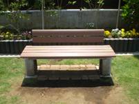 コンクリートの脚で支えられている木製の座面と背もたれを持つシンプルなデザインのベンチの写真