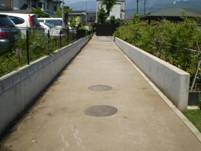 コンクリートの壁に挟まれた通路上にマンホールが2つ設置されている写真