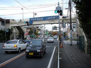 歩道橋下を通る片側一車線の道路が多くの車で込み合っている様子の写真