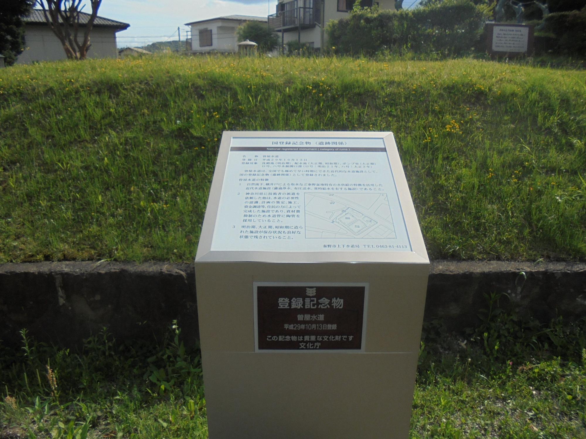 芝生の斜面と石積みの土台の上に立てられた、国登録記念物をクローズアップした写真