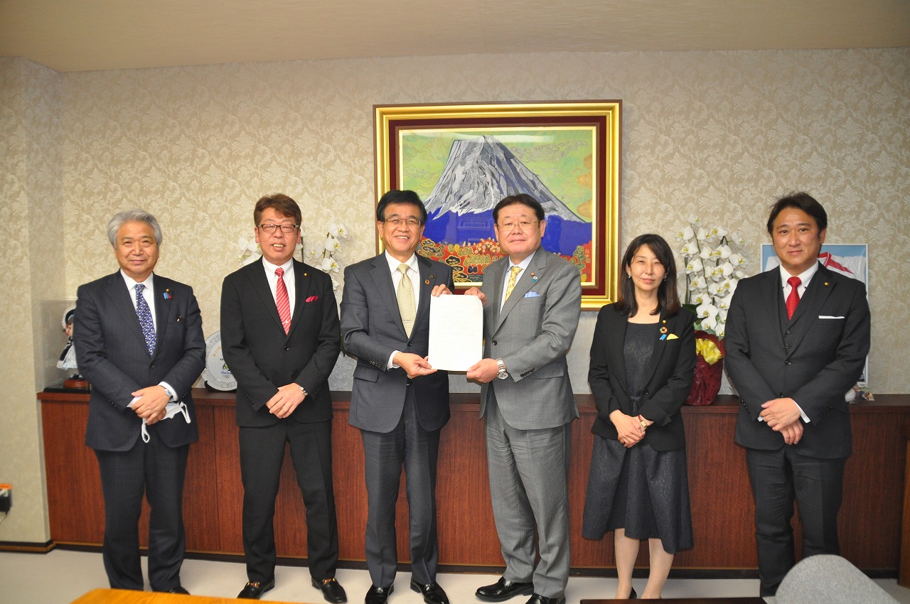 中央で高橋市長と男性が要望書を一緒に持ち、2人の両側にスーツを着た男女4人が並び記念撮影を行っている写真