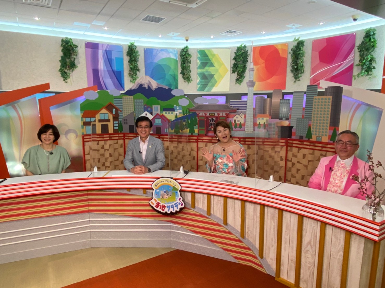 背景にスカイツリーや富士山のパネル、カラフルなセットが組まれたテレビスタジオで「ご当地サタデー」に出演している高橋市長の写真