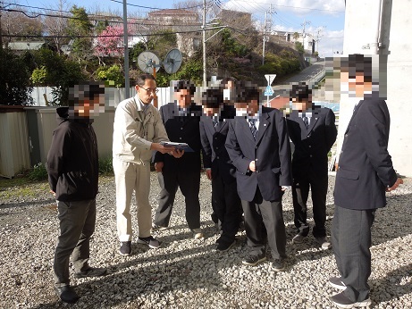 作業服姿の男性から書類を見せながら説明を受けている様子の写真