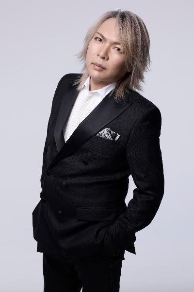 白いワイシャツの上にまだら模様のチーフを挿した黒のスーツをまとっているルナシー真矢さんのアーティスト写真