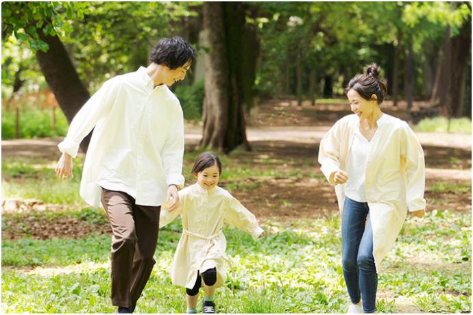 白い服を来た家族3人が歩いている様子の写真