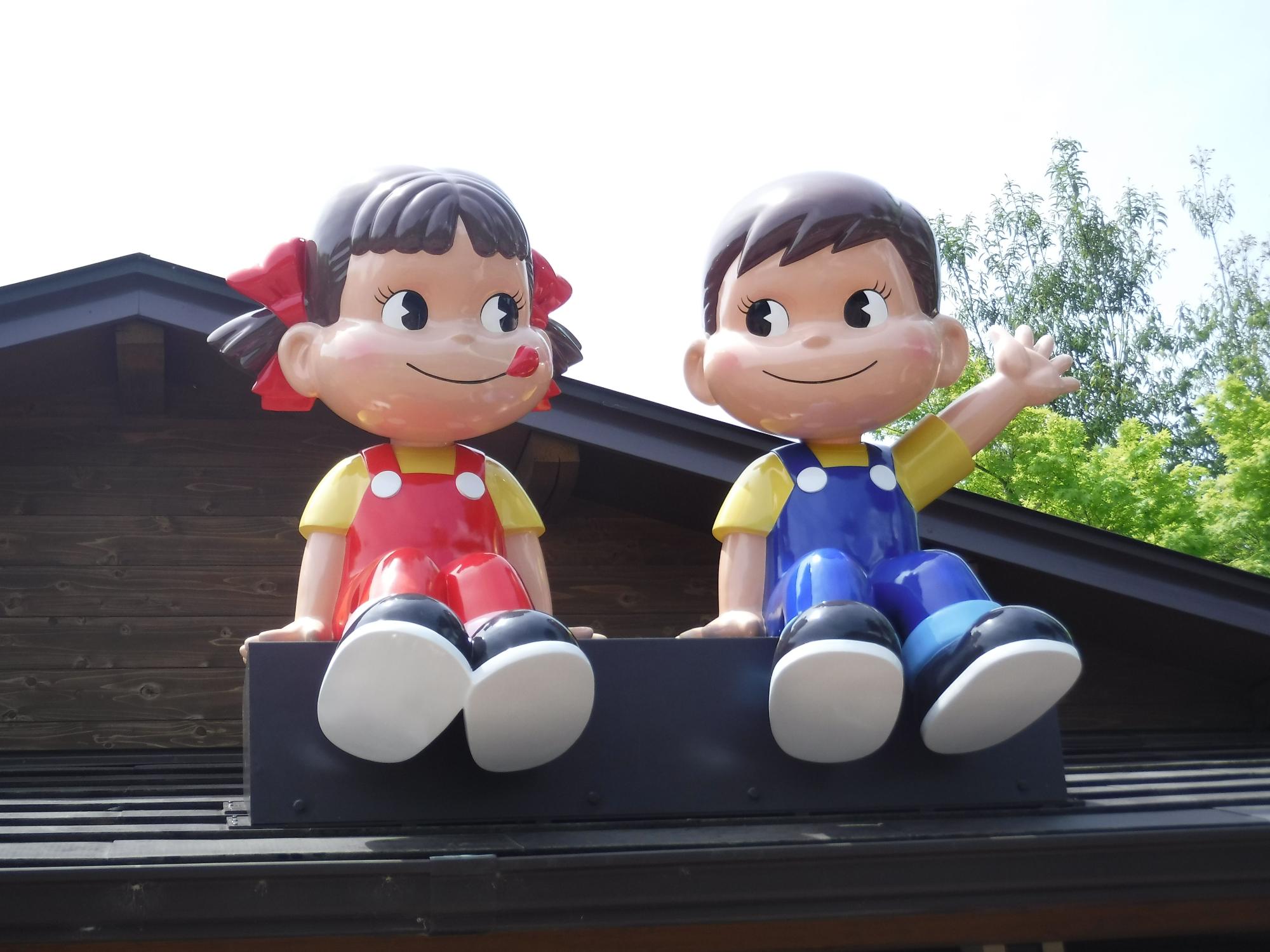 ペコちゃんとポコちゃんがベンチに並んで座ったが並んで座っているオブジェの写真