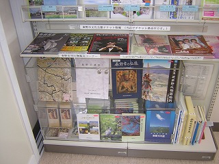 秦野市に関する様々な地図や書籍、イベントのチラシなどが、クリアケースや棚に整然と陳列された市の刊行物コーナーの写真