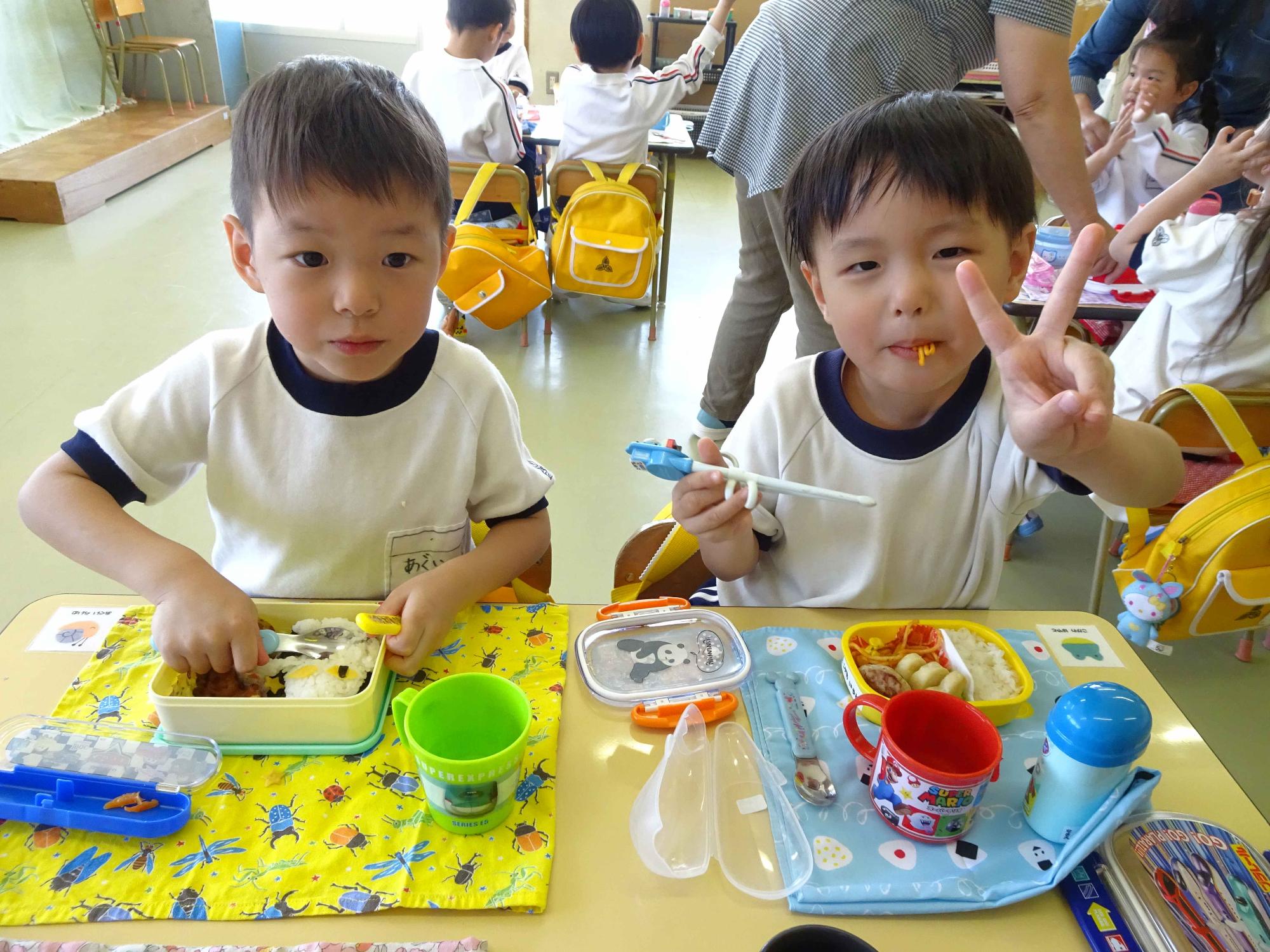 子ども達が保護者の作ってくれた弁当を食べながら、嬉しそうにピースサインをしているところです。