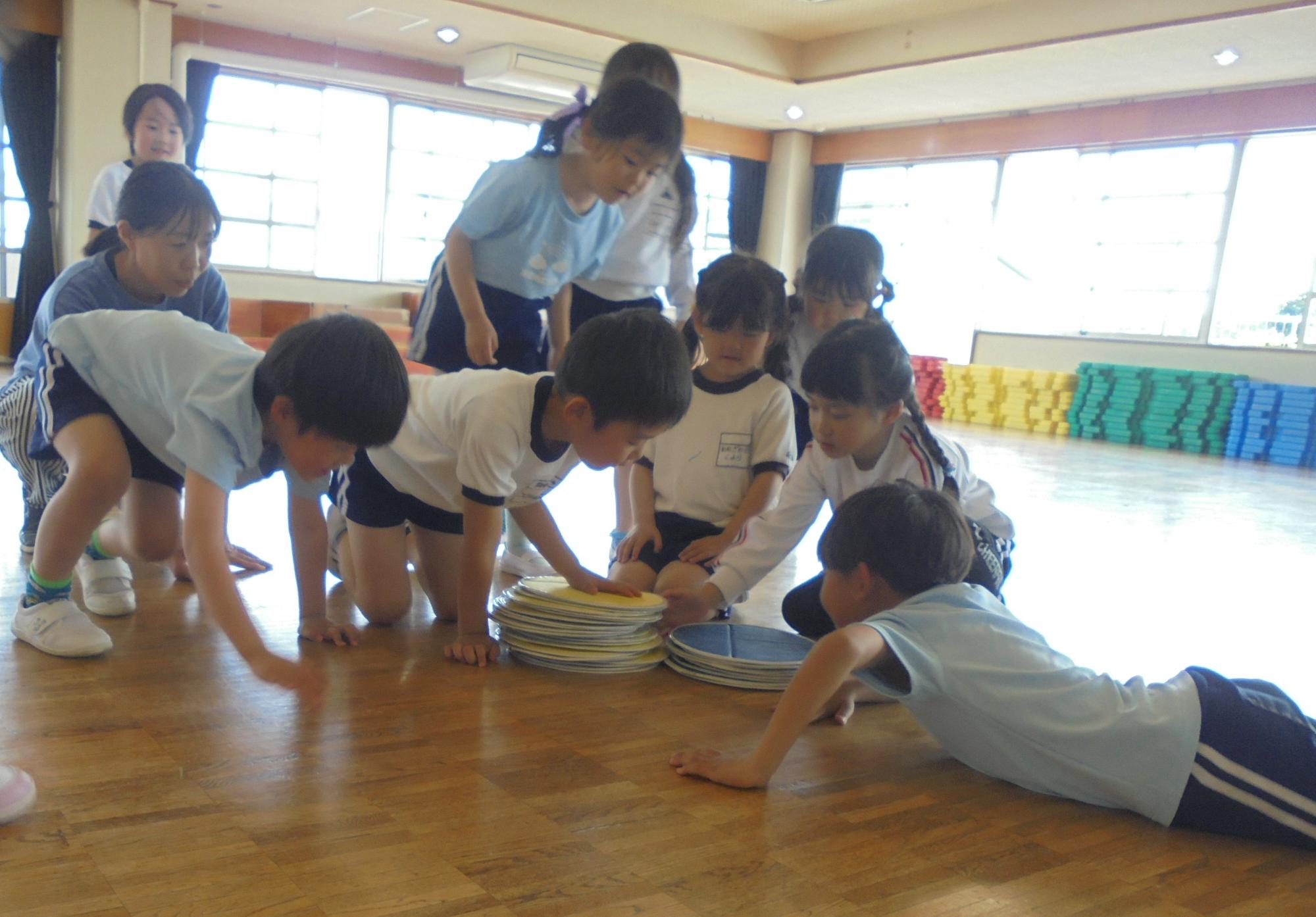 大型オセロゲームをし、どちらのチームが勝ったか子ども達がオセロを積み上げて調べているところです。