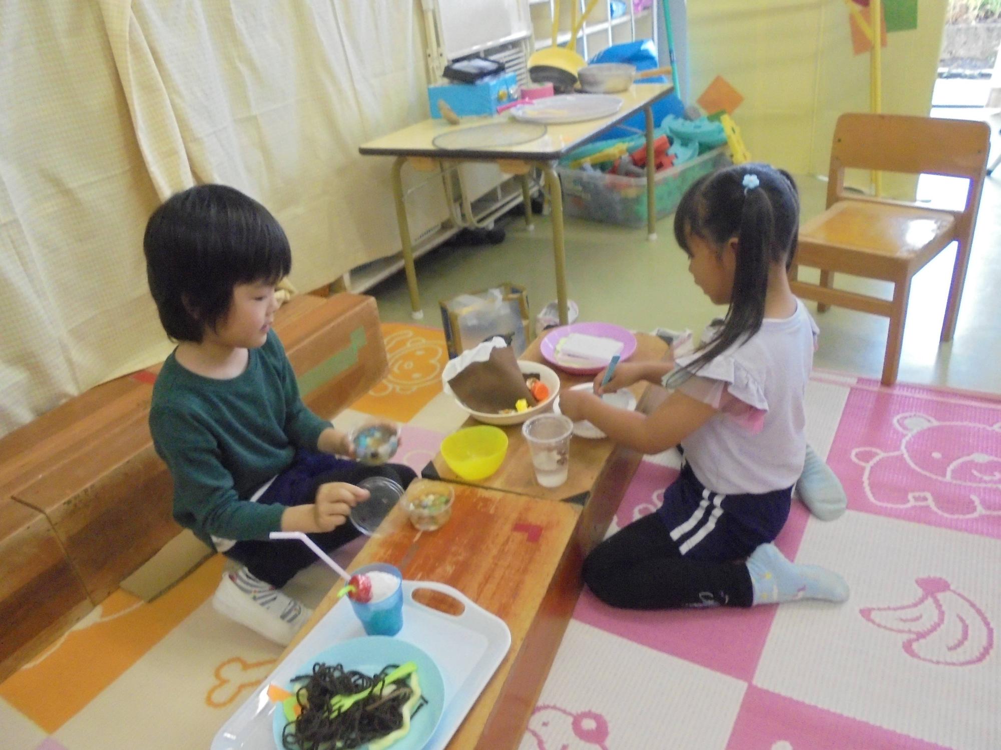 ままごと遊びをしている2人が料理を作って食べようとしているところです。