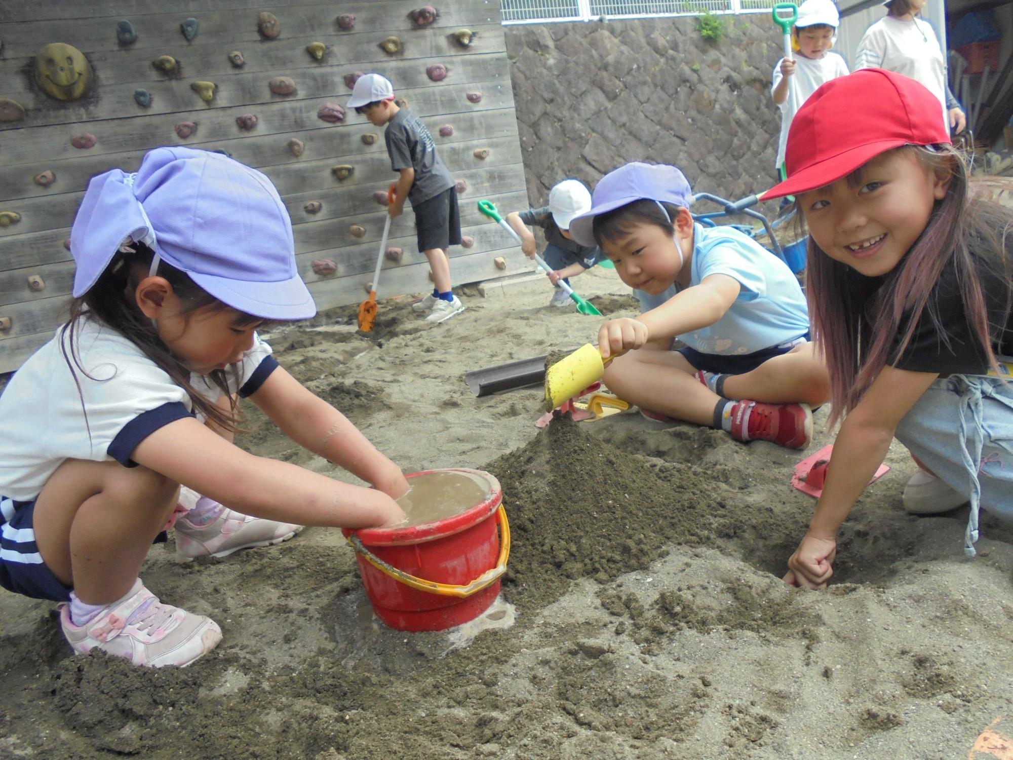 隣の小学校の一年生と一緒に砂場で遊んでいるところです。