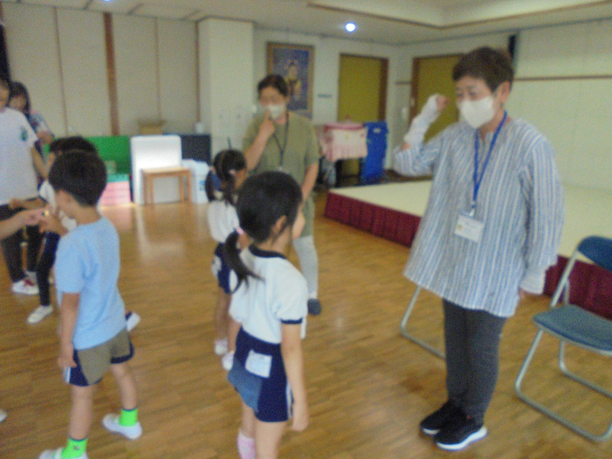 幼稚園のホールで民生委員の方たちと年長児がじゃんけんゲームをしているところです。