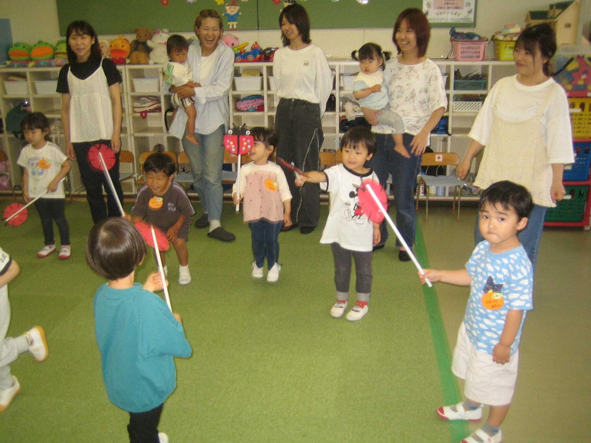 親子で制作したテントウムシを、棒の先に付けて動かして遊んでいます。