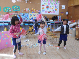 衣装を身に着けバチをもって3名の園児が踊っている