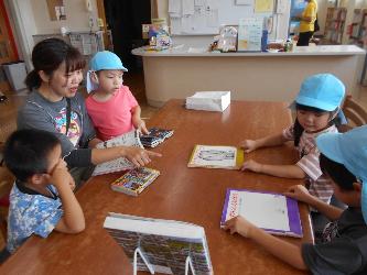 小学校の図書室で絵本を読む先生と子ども達