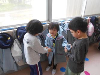年長児が年少児に園服を着る手伝いをしている