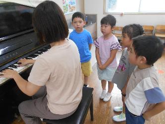 先生のピアノに合わせて子ども達が歌を歌っている