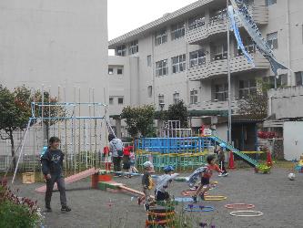 園庭で先生と子ども達が元気に走っている