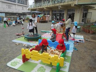 年少の子ども達が先生や友達と基地づくりをして遊んでいる