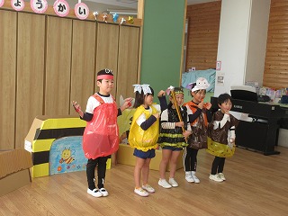 園児たちがビニール袋などを再利用して作った赤色のてんとう虫や黄色と黒色のハチ、茶色のカブトムシなどの昆虫の衣装を身につけ、楽しそうに発表会をしている様子の写真