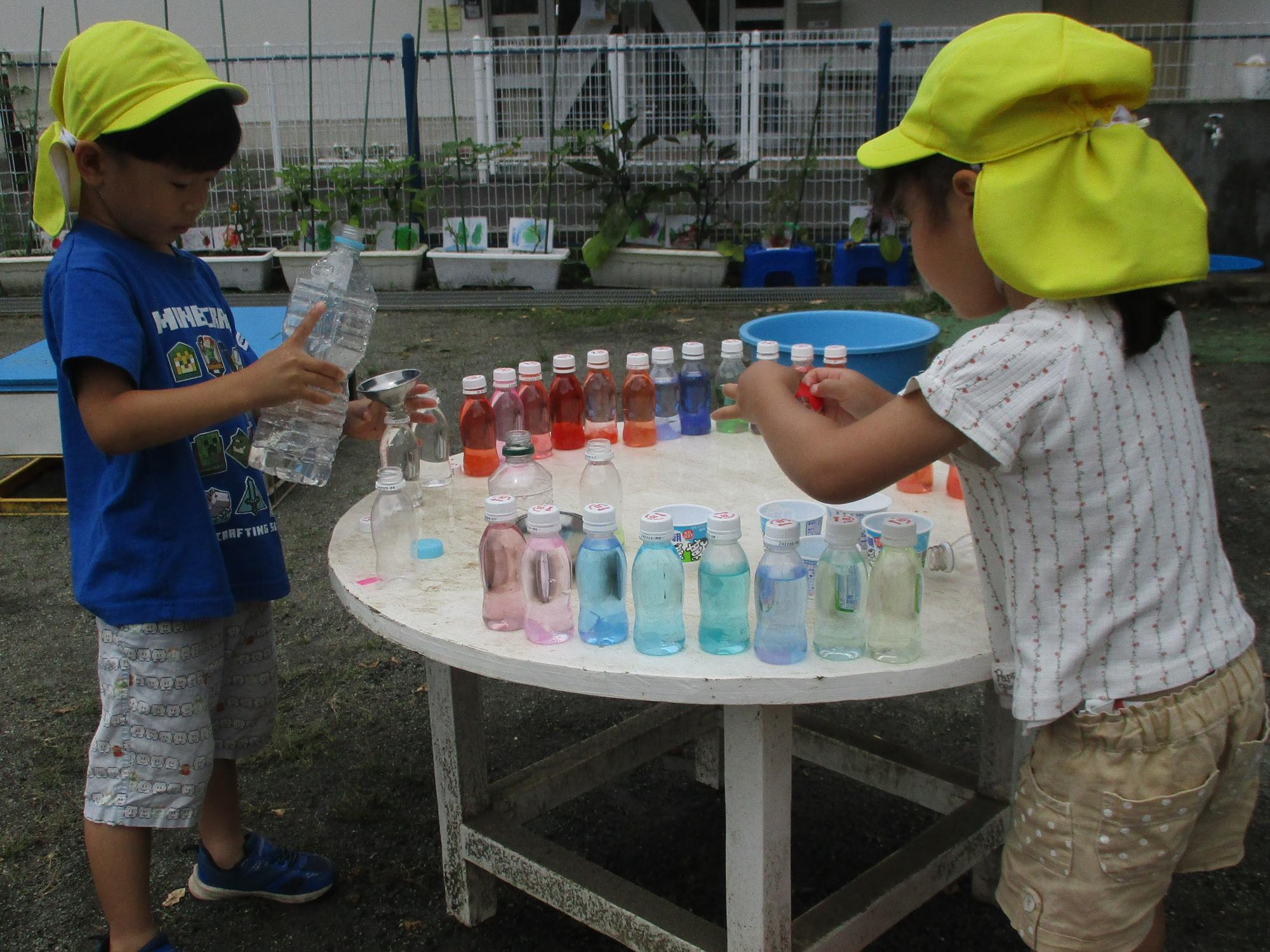 子ども達が色々な色水遊びを楽しんでいる