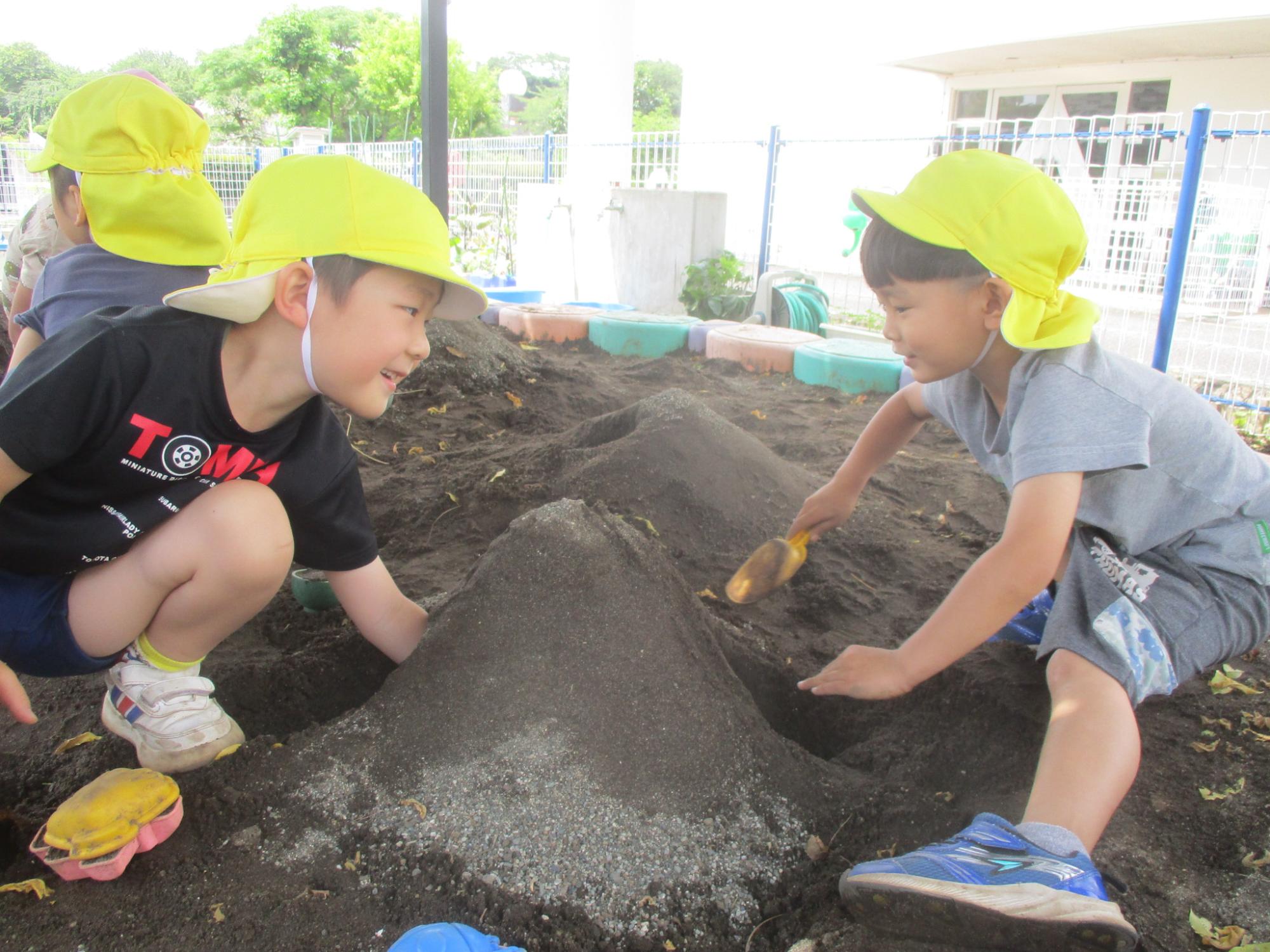 砂場遊びで山を作り、穴を掘っている